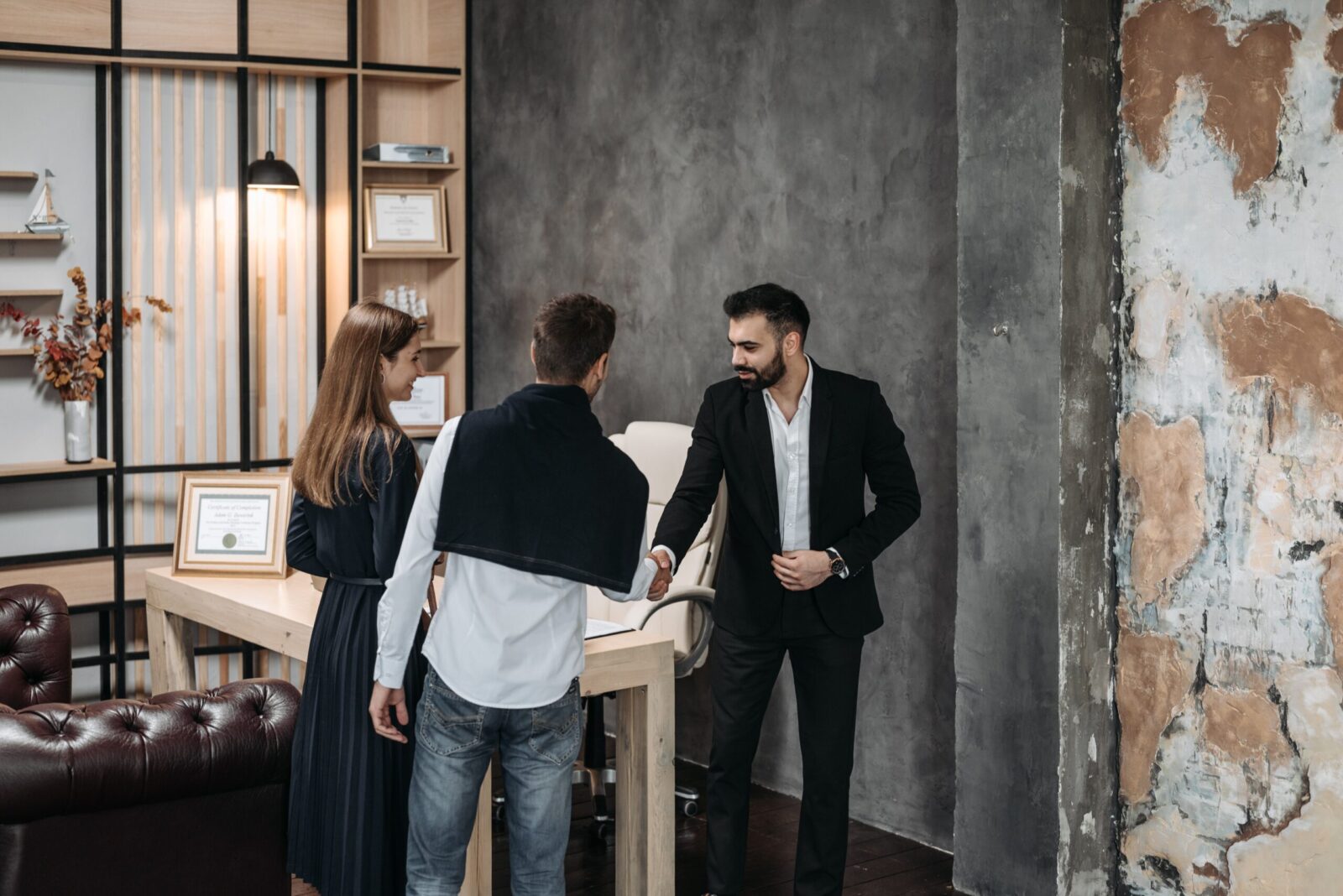 Business professionals discussing in a stylish, modern office setting with a handshake agreement.