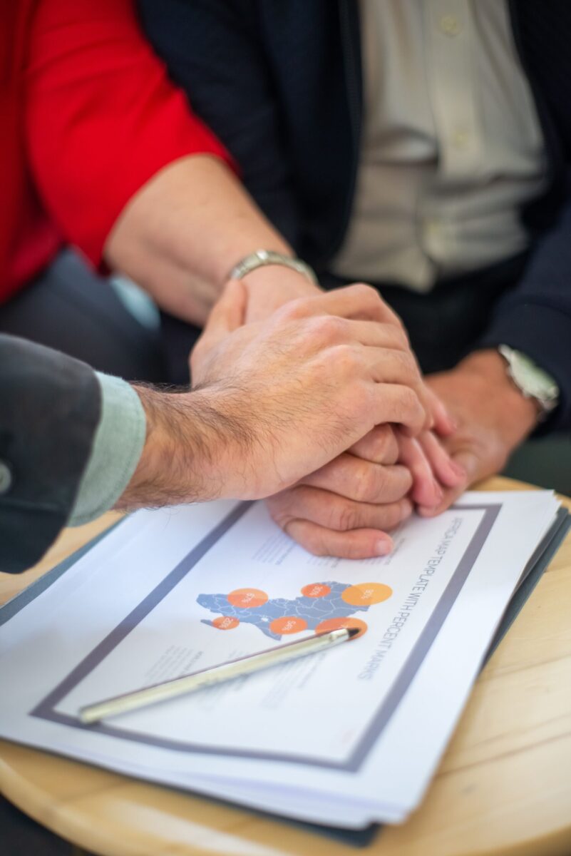 Close-up of hands together over business documents symbolizing teamwork and collaboration.